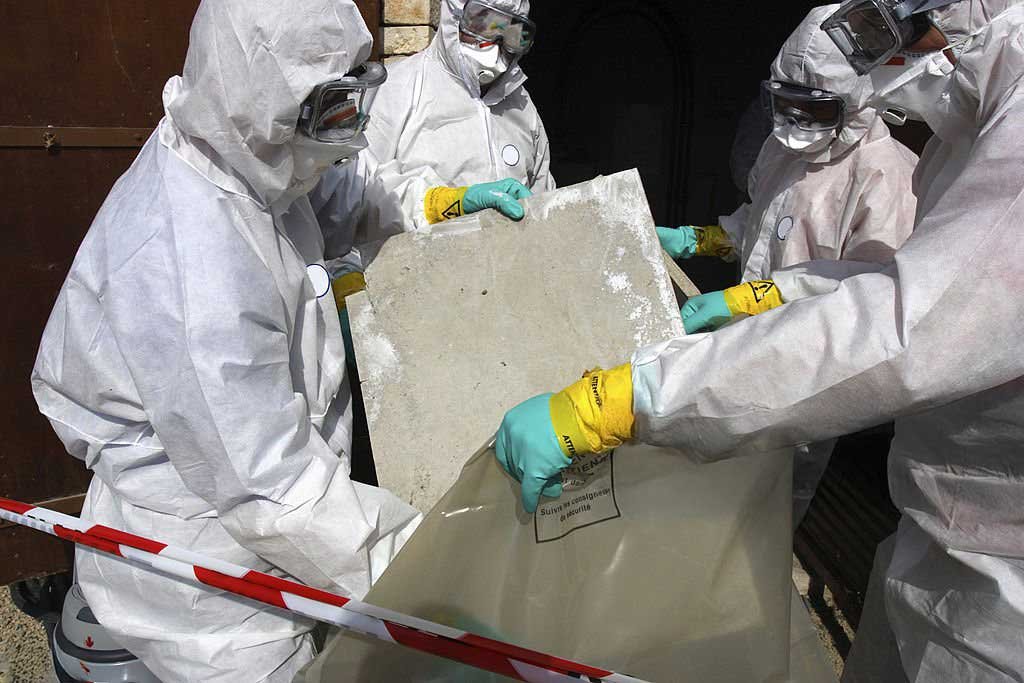 Équipe en combinaison de protection manipulant un panneau contenant de l’amiante à Bruxelles – Asbestteam verpakt gevaarlijk materiaal volgens veiligheidsvoorschriften